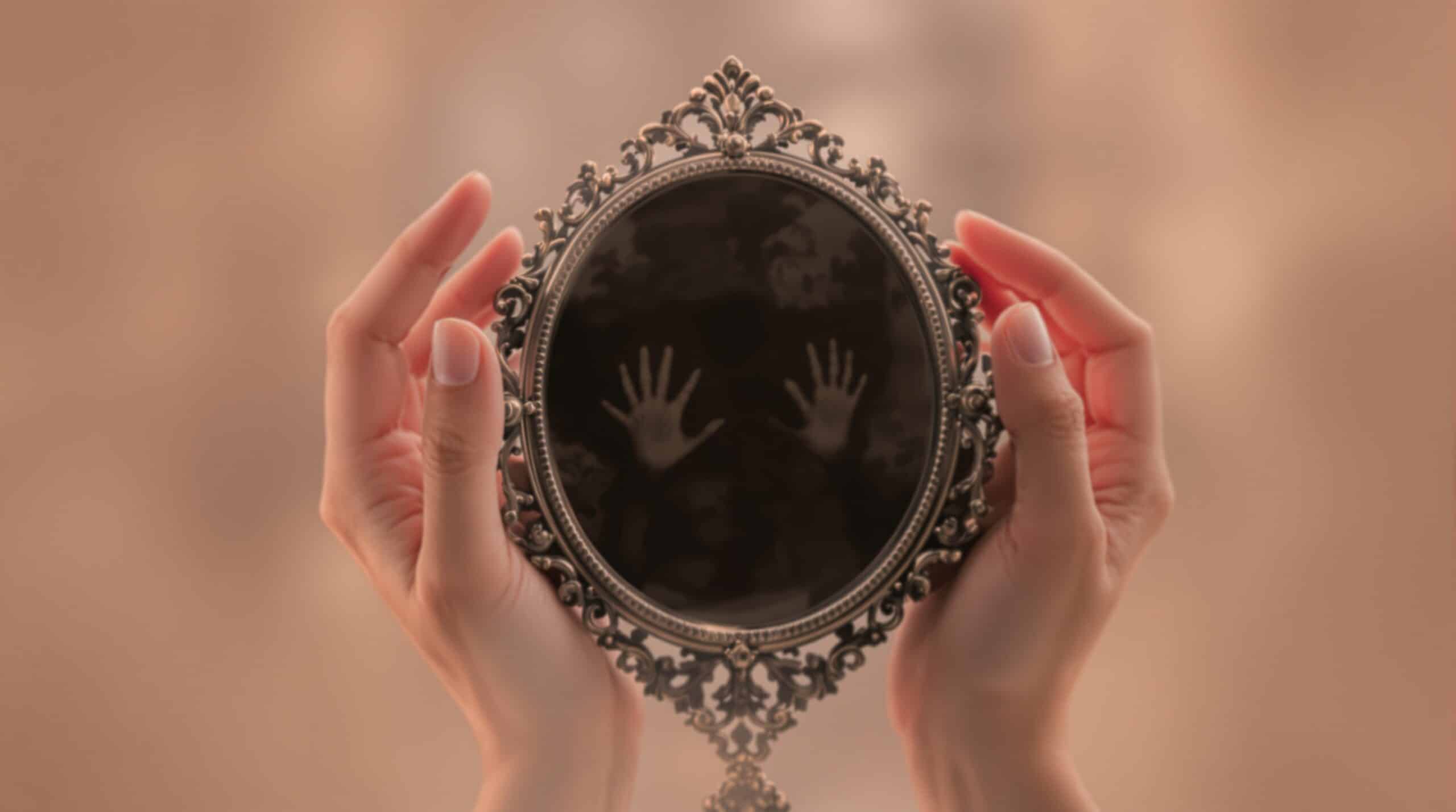 Hands holding ornate vintage mirror reflecting darkness, symbolizing hidden self-discovery in shadow work journal practice