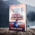 Alt text: "Book cover mockup of '100 Mental Health Journaling Prompts' by Richard French, featuring a woman sitting cross-legged while writing in a journal with artistic tree branches extending from her head, set against a desert landscape with floating journal pages, displayed on wooden planks with a blurred mountain background.